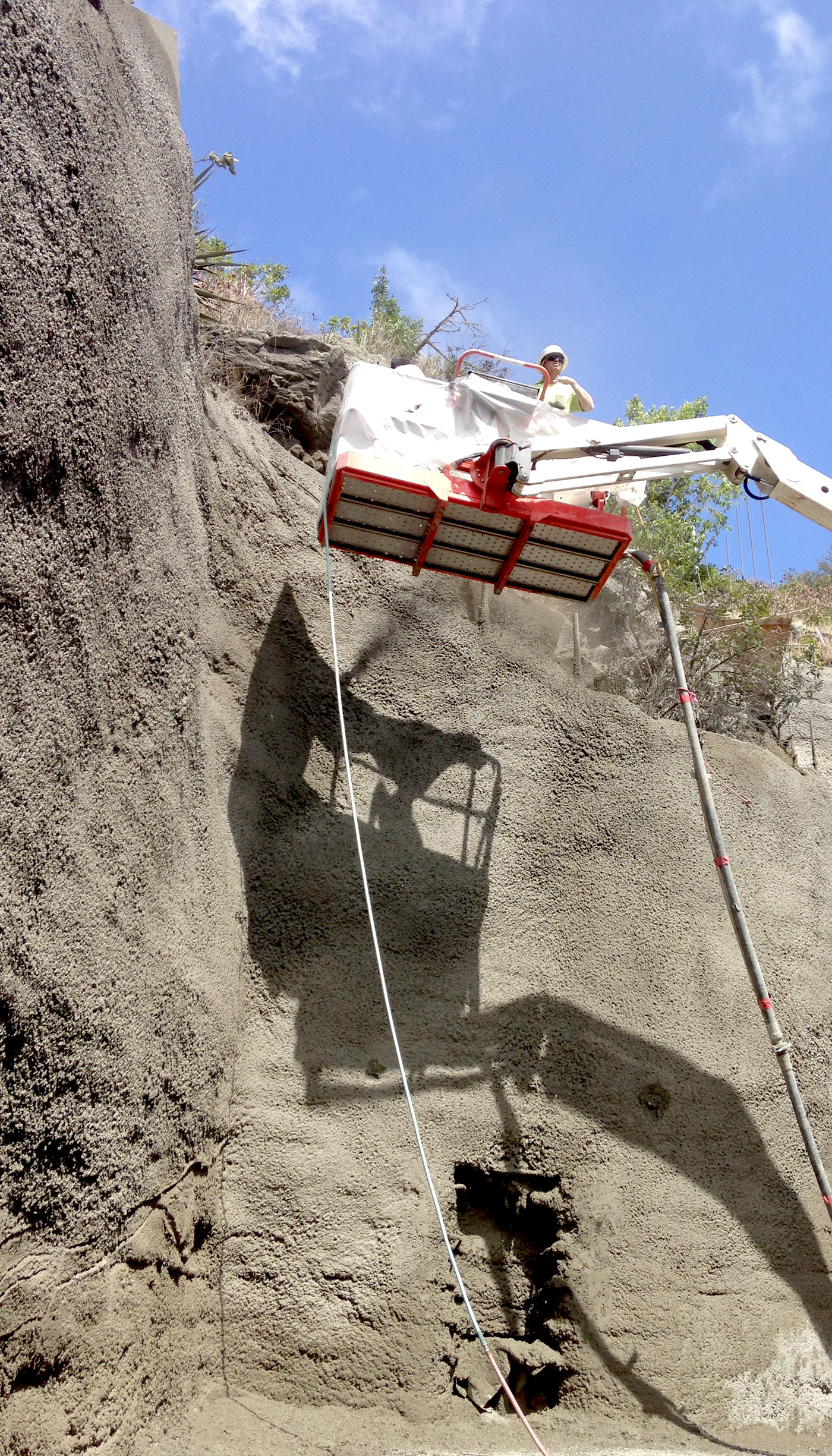 Photo: tall retaining wall, shotcrete, and cherry picker lift, preparing to apply texture, detail